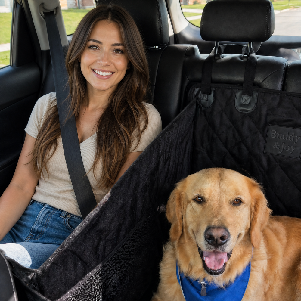 A golden retriever dog wearing a blue bandana sits in a black mesh and quilted pet car seat inside a car, with a smiling woman in the front seat next to it. using Buddy & Joy hammock